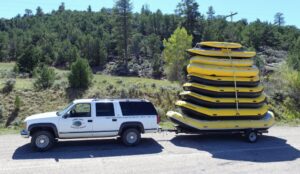 Green river rafts on trailer ready to be launched into the river 2 miles from Dutch John Resort. Inflatable rubber Rafts in image seat 4-15 riders who paddle the raft through the cool clear waters surrounded by the 500-700 foot tall Red Canyon walls bordering the river.