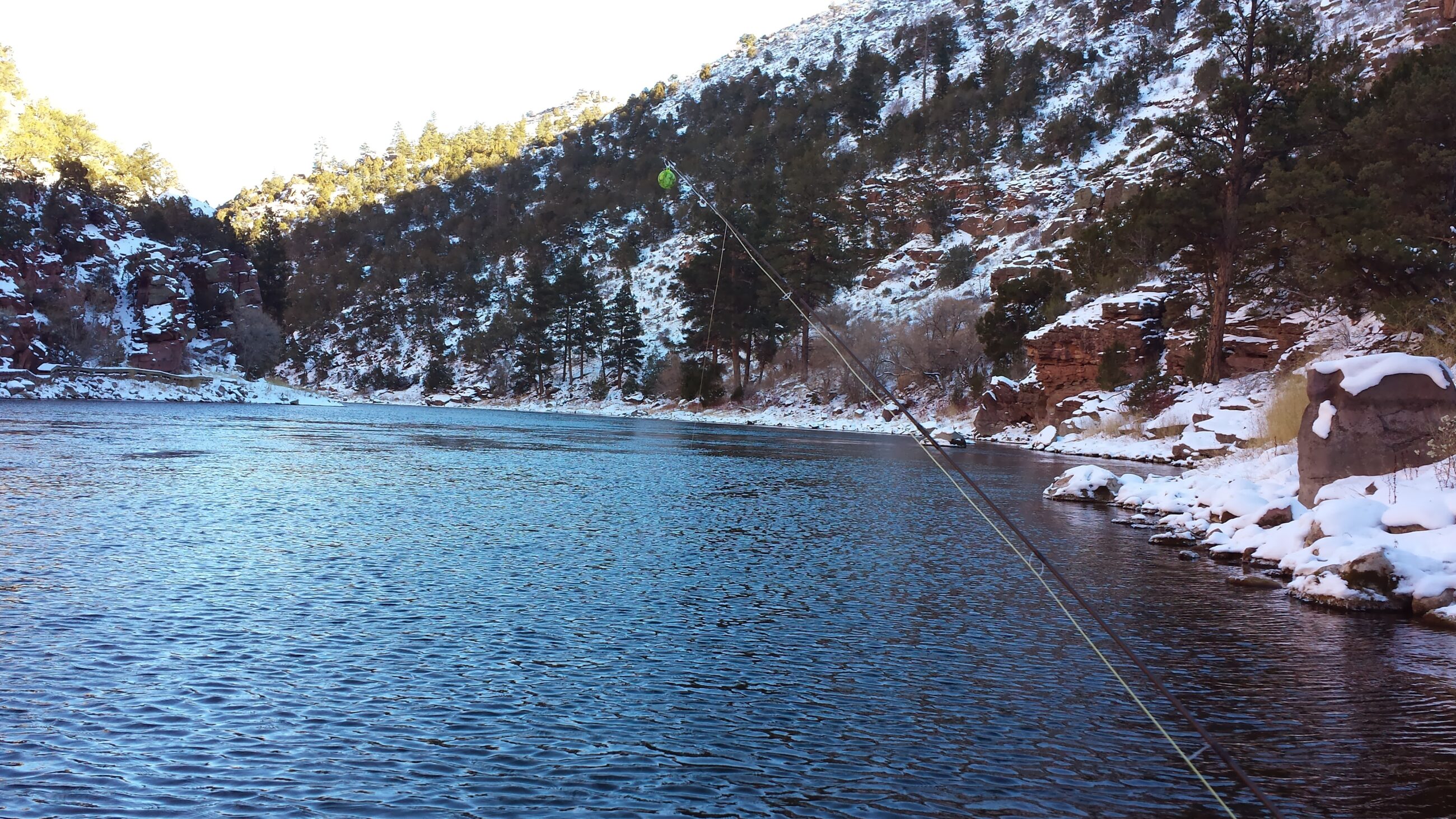 Drift boat on the Green river pulled into a calm eddie to allow Green river fishing guide and 2 fly fishing guests to stretch their legs on the shore & to cast dry flies to trophy size trout swimming in the Gin Clear waters of the Green river feeding on a hatch of Blue Wing Olive May Flies.