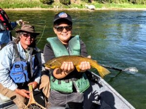 Fly Fishing Couple With Green River Fly Fishing Guide Floating In A Drift Boat From Dutch John Resort releasing a wild Green River Brown Trout safely back into his home.