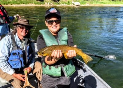 Fly Fishing Couple With Green River Fly Fishing Guide Floating In A Drift Boat From Dutch John Resort releasing a wild Green River Brown Trout safely back into his home.