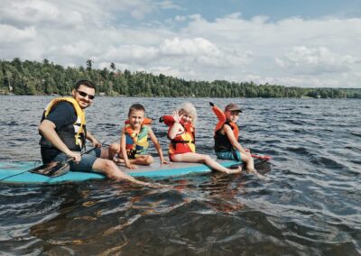 a father and three kids in a stand up padle in the lake