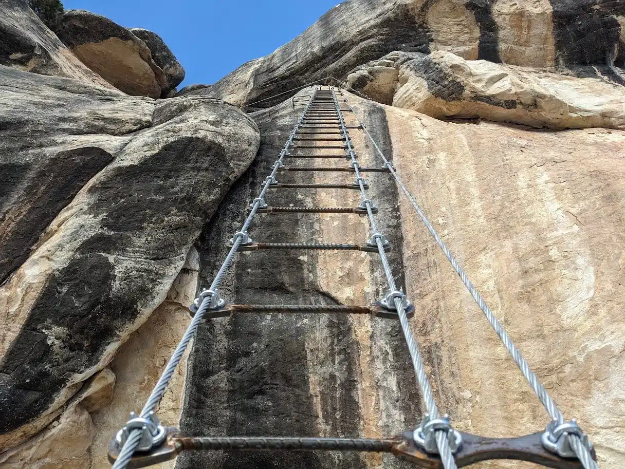 Via ferrata rungs and steel safety cable set into the sandstone wall of Ashley Gorge